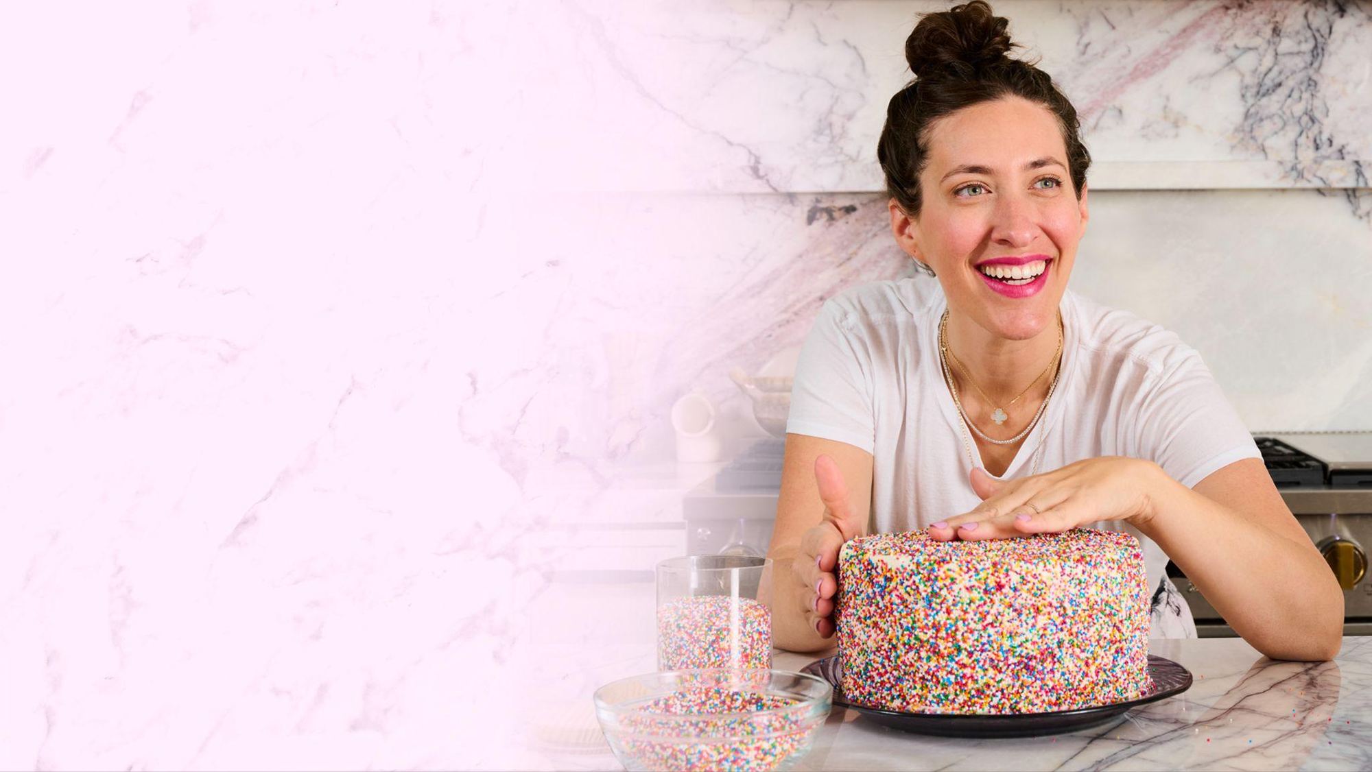 Dana Pollack smiling with a sprinkle-covered cake