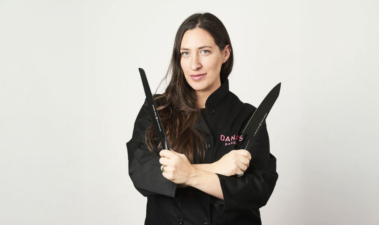 Dana Pollack in chef whites holding two knives
